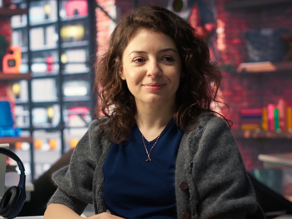 A developer smiles at her desk while coding in an agency office